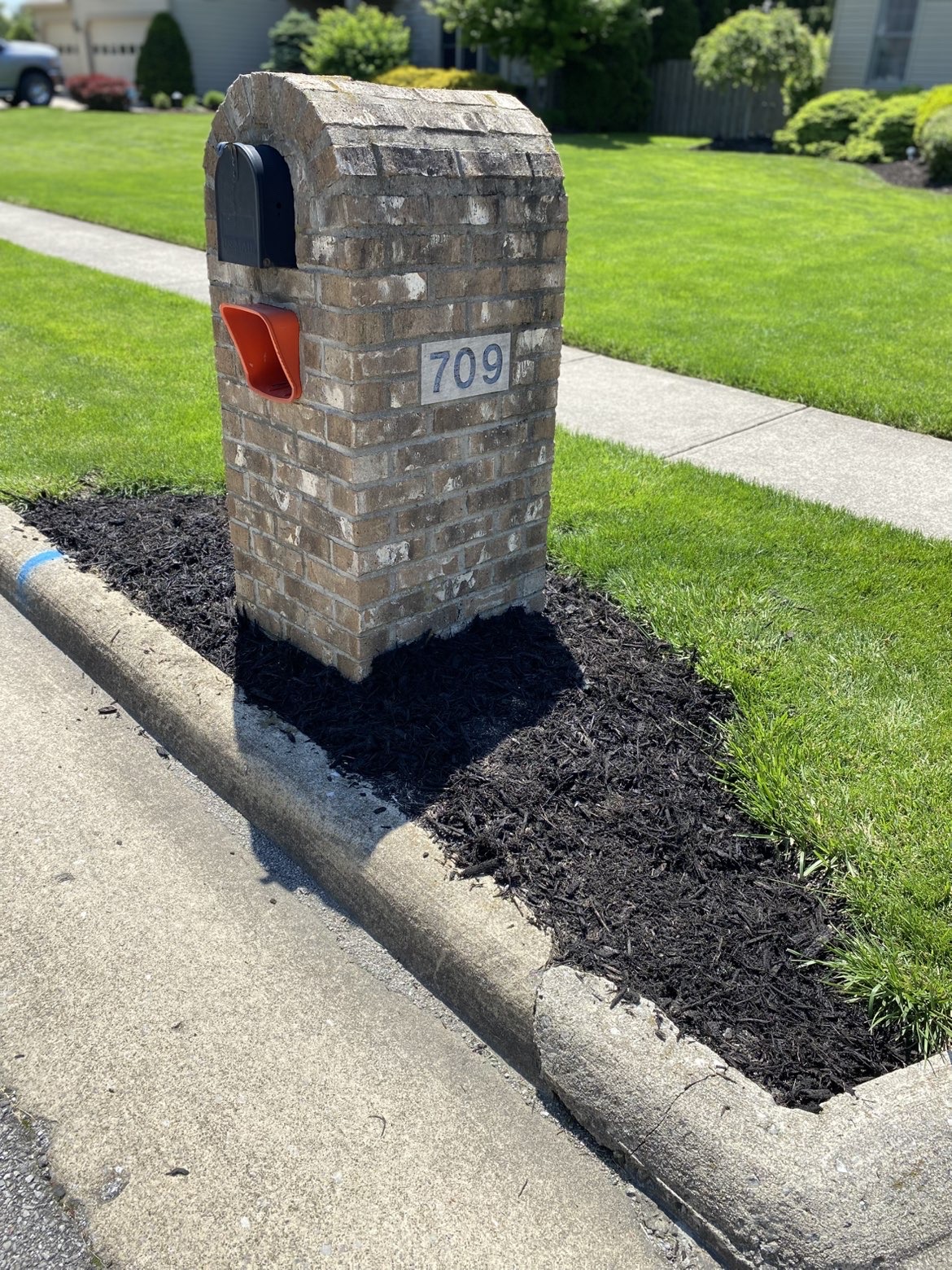 Brick mailbox with fresh black mulch surround and green lawn